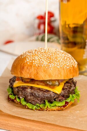 Cheeseburger pierced by a wooden skewer shot on a wooden boardの写真素材