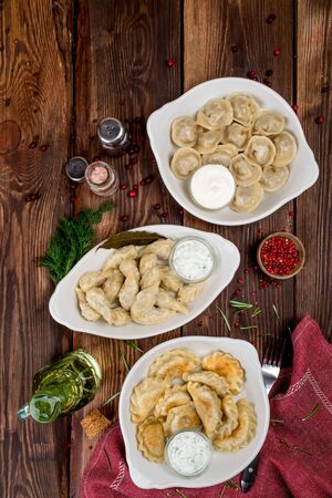 Dumplings and dumplings with sour cream and pepper shot on a wooden background from aboveの写真素材