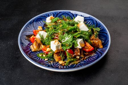 Close-up shot of a salad with eggplant and fresh herbs on a black backgroundの写真素材
