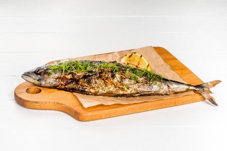 Grilled mackerel served with lemon served on a wooden board shot on a white backgroundの写真素材