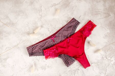 A set of women's panties of red color shot on a textured background from above