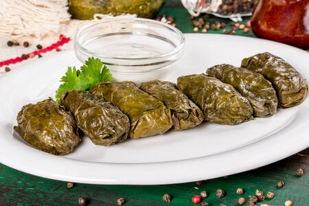 Dolma with sauce on a white plate. Close-up side view