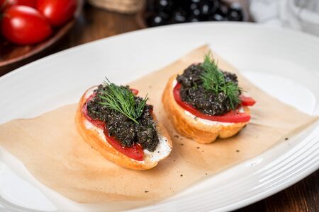 Bruschetta with olive paste on a white plate. Close-up shotの写真素材