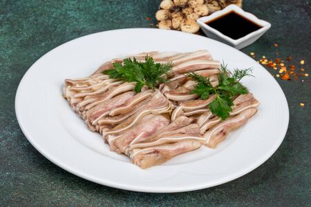 Dish of pork ears sliced on a white plate. Close-up shot