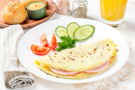 Breakfast omelet with vegetables on a white, round plate. Close-up shotの写真素材