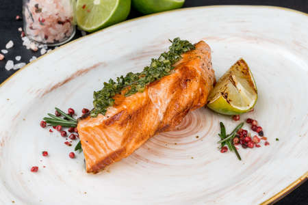 One slice of grilled salmon on a white plate. Close-up shotの写真素材