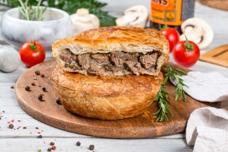 Oven-cooked meat pie served on a round wooden board. Close-up shot
