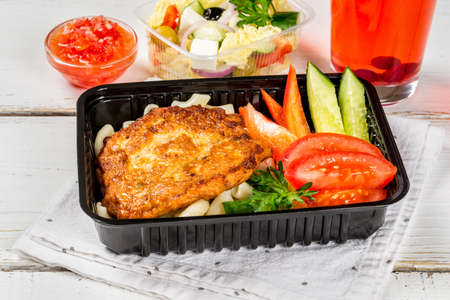 Cutlet with pasta, vegetables in a black container. Close-up shotの写真素材
