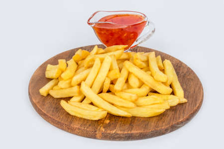 Ready french fries on a round wooden board with sauce