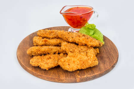 Nuggets on a wooden round board with sauce on a white backgroundの写真素材