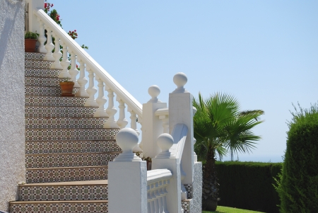 Spanish style exterior staircase, typical of maritime zones, white and Andalusian tiles, potted flowers and plantsの写真素材