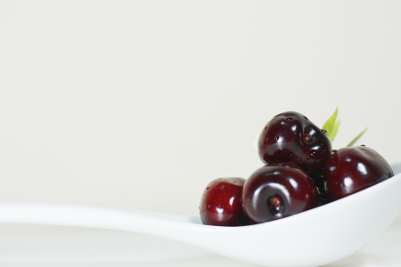 Cherries on white background natural fruit on white porcelain spoonの写真素材