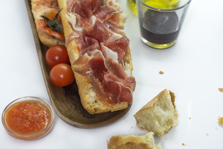baguette with jamon iberico, tomato on wooden boardの写真素材