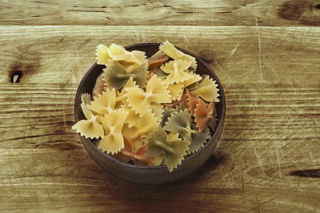 Italian pasta, vegetables ties in rustic bowl on wood backgroundの写真素材