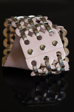 pink leather belt with metal clasps on black backgroundの写真素材