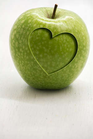 Green apple with carved heart, conceptual health and wellnessの写真素材