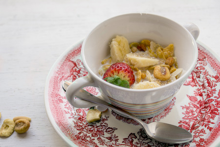 Breakfast in the sun, cereal bowl, strawberry and banana, yogurt on blue plate Close-upの写真素材
