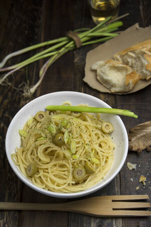 bowl of spaghetti, olives with anchovies and olive oil on dark wood and rustic environment.の写真素材