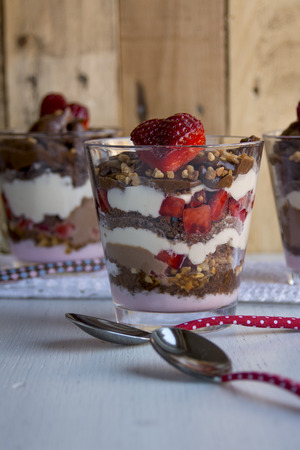 dessert, chocolate cream, yogurt, fresh strawberries and whipped cream on wooden backgroundの写真素材
