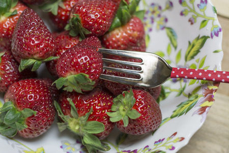Strawberries on plate, cutlery and napkin on wooden background の写真素材