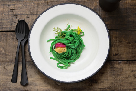 Green spaghetti, dyed with food coloring on rustic wooden table の写真素材
