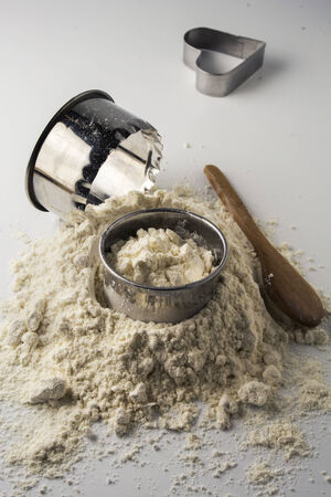 pastry cutters and flour on white wooden boardの写真素材