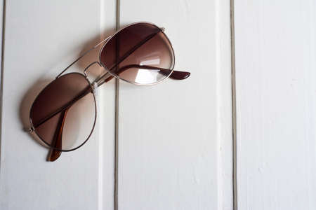 Sunglasses with brown glass on white wooden backgroundの写真素材