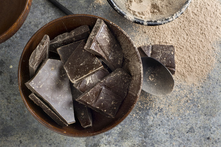 dark chocolate chunks in wooden bowl, on oak tableの写真素材