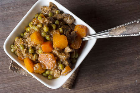 hot beef stew with carrots and tomato sauce, on wooden backgroundの写真素材