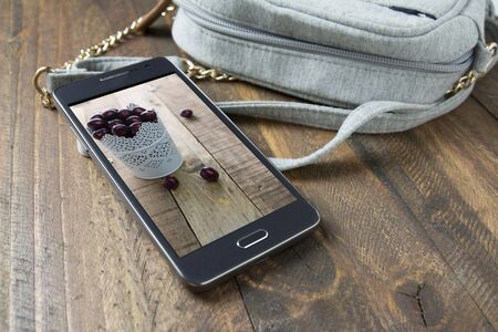 Mobile phone and handbag women ond wood backgroundの写真素材