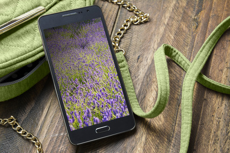 Mobile phone with background of flowers and hand bag womanの写真素材