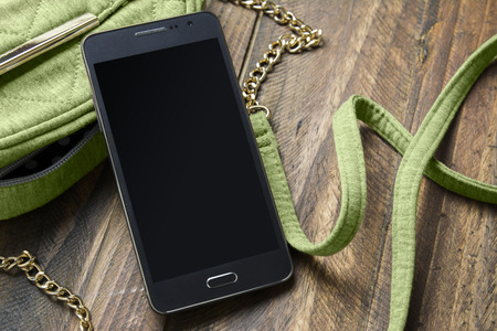 Mobile phone and handbag women ond wood backgroundの写真素材