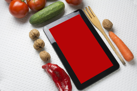 Digital tablet with fresh vegetables on white backgroundの写真素材