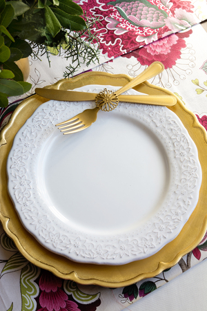 christmas place setting, table ready for lunch, on golden plates and white patterned background in flowersの写真素材