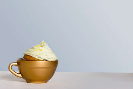 Cupcake with frosting and sprinkles, inside a small golden cupの写真素材