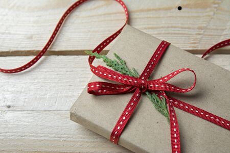 Gift box, wrapped in recycled paper and red bow on wood backgroundの写真素材