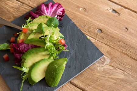 Avocado and ettuce salad on wooden background