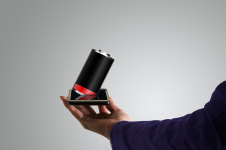 Business woman, hand holding a touch phone, with low battery out of the screen, gray background