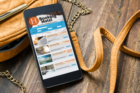 smart phone, with online hotel booking next to the woman's purse. Travel and tourism conceptの写真素材