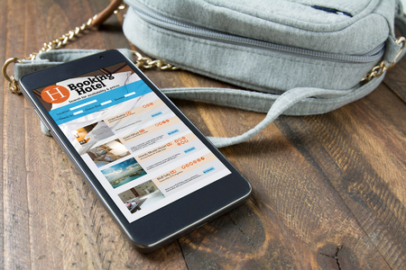 smart phone, with online hotel booking next to the woman's purse. Travel and tourism conceptの写真素材