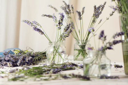 Small bouquet of fresh lavender in jars with water, on wooden tableの写真素材