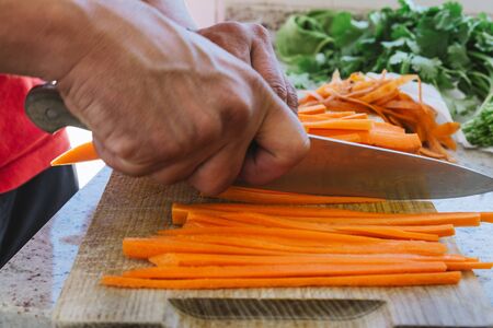 man's hands, cut carrot julienne style, in the kitchenの写真素材
