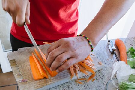 man's hands, cut carrot julienne style, in the kitchenの写真素材