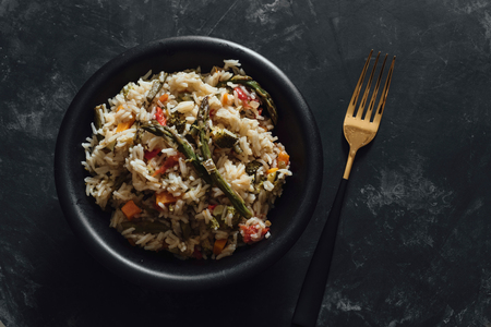 Bowl with basmati rice with sauteed vegetables, on black tableの写真素材