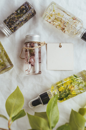 Essential oil, empty tags and fresh almond flowers, on green leaves backgroundの写真素材