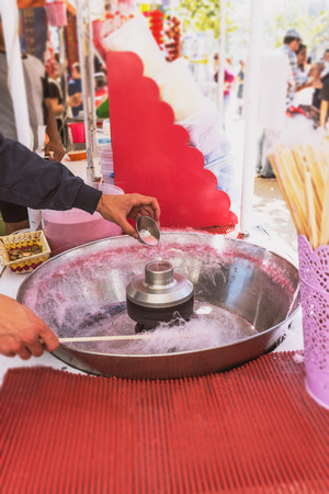 Pink cotton candy. Salesman are spinning the color of sugar with a spinning step. Sweet taste by food machine processの写真素材