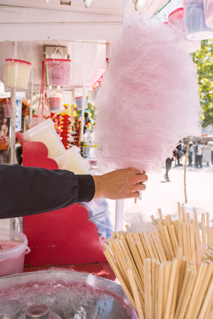 Pink cotton candy. Salesman are spinning the color of sugar with a spinning step. Sweet taste by food machine processの写真素材