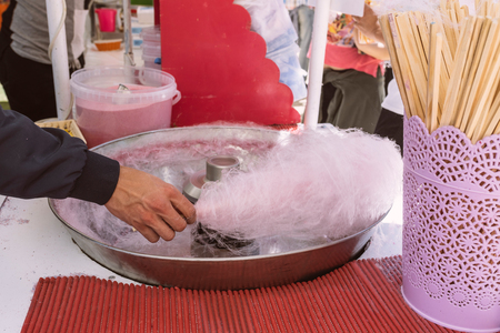 Pink cotton candy. Salesman are spinning the color of sugar with a spinning step. Sweet taste by food machine processの写真素材