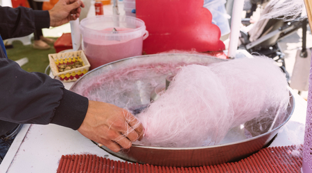 Pink cotton candy. Salesman are spinning the color of sugar with a spinning step. Sweet taste by food machine processの写真素材