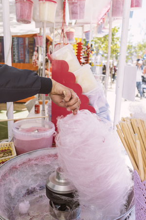 Pink cotton candy. Salesman are spinning the color of sugar with a spinning step. Sweet taste by food machine processの写真素材